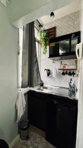 una pequeña cocina con fregadero y ventana en Estúdio charmoso na Lapa, en Río de Janeiro