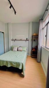 Un dormitorio con una cama verde y una ventana en Estúdio charmoso na Lapa, en Río de Janeiro