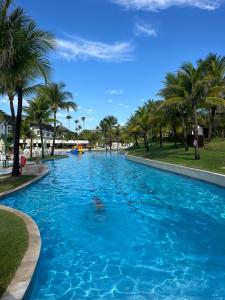 uma grande piscina azul com palmeiras num parque em Beach Class Muro Alto Resort - flats e bangalôs em Porto de Galinhas