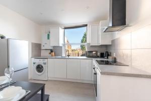 a kitchen with white cabinets and a washer and dryer at Ivy House - 3 Bedroom House - Contractor Stay in Bristol