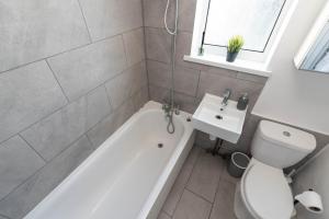 a bathroom with a tub and a toilet and a sink at Ivy House - 3 Bedroom House - Contractor Stay in Bristol +15 photos