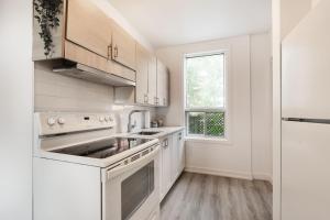 uma cozinha branca com electrodomésticos brancos e uma janela em Appartement 1 chambre-1011 em Montreal