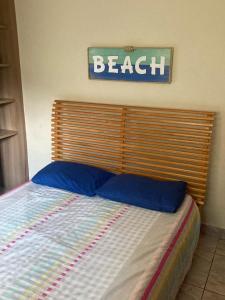 - un lit avec une tête de lit en bois et un panneau de plage sur le mur dans l'établissement CASA DE PRAIA COM PISCINA e AREA GOURMET, à Caraguatatuba