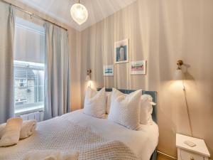 a bedroom with a bed with white sheets and a window at Coral Cottage in Amble