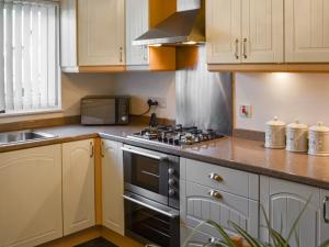 cocina con armarios blancos y fogones en The Malt House en Rothbury