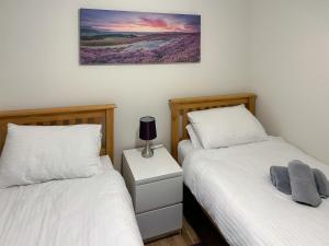 a bedroom with two beds and a lamp on a night stand at The Malt House in Rothbury