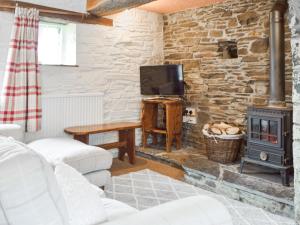 a living room with a stone wall and a wood stove at Ty Tarw - Uk46189 in Llanybyther