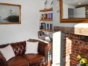 a leather couch in a living room with a brick fireplace at The Apricot Tree in Carisbrooke