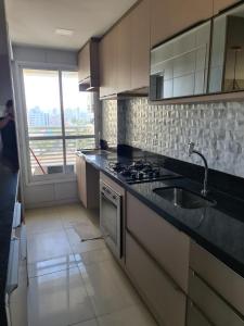 cocina con fregadero, fogones y ventana en Apartamento Praia do Futuro mobiliado, en Fortaleza