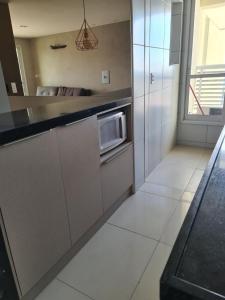 a kitchen with a counter with a microwave in it at Apartamento Praia do Futuro mobiliado in Fortaleza