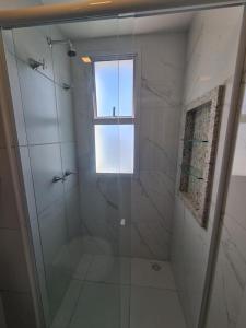 a bathroom with a glass shower with a window at Apartamento Praia do Futuro mobiliado in Fortaleza