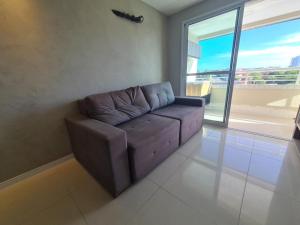 a couch in a living room with a large window at Apartamento Praia do Futuro mobiliado in Fortaleza