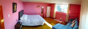 a bedroom with pink walls and a bed and a couch at Casa Victoria in Cusco