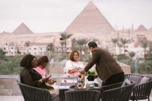 a group of people sitting around a table in front of the pyramids at Tuia pyramids hotel in Cairo