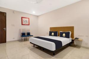 a bedroom with a large bed and a chair at Townhouse OAK De Alphabet Hotel Bolarum in Hyderabad