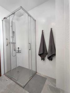 y baño con cabina de ducha de cristal y toallas. en Casa Mirador del Puente en Arcos de la Frontera