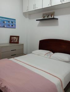 1 dormitorio con 1 cama con sábanas blancas y armario en La Silvita - Casa de playa, en Los Órganos