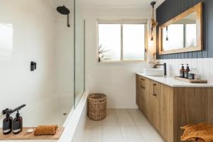 y baño con bañera, lavamanos y ducha. en Lobster Pot Cabin, en Coles Bay