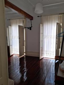 an empty living room with white curtains and wooden floors at Ninho do Corvo in Torre de Moncorvo