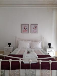 a white bedroom with a bed with two pictures on the wall at Ninho do Corvo in Torre de Moncorvo