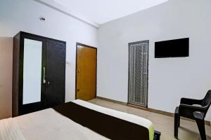 Un dormitorio con una cama y una silla y un televisor. en Hotel O MOHAPATRA GUEST HOUSE, en Khandagiri