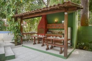 a wooden pavilion with two benches and a table at Pousada Sonhos de Praia, Fácil Acesso a Praia, Rua Mucugê e Beco das Cores in Arraial d'Ajuda