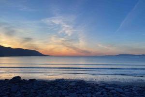 a sunset over the ocean with rocks on the beach at Mountain View House in Killarney