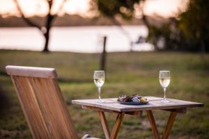 una mesa con dos copas de vino y un plato de comida en Lobster Pot Cabin, en Coles Bay
