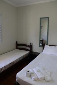 two beds in a room with towels and a mirror at Camping Pousada Ilha do Mel - Frente ao Mar in Boracéia