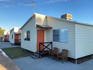 a white house with two chairs and a table at Longreach Private Apartments in Longreach