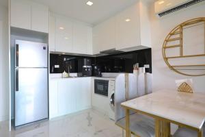 a white kitchen with a refrigerator and a table at Pratamnak Pattaya Luxury Condo, Golf, Ocean View in Pattaya South