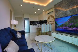 a living room with a blue couch and a large tv at Pratamnak Pattaya Luxury Condo, Golf, Ocean View in Pattaya South