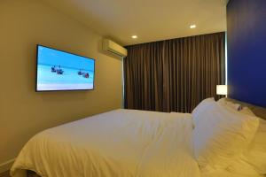 a hotel room with a bed and a flat screen tv at Pratamnak Pattaya Luxury Condo, Golf, Ocean View in Pattaya South