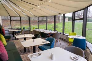 um restaurante com mesas, cadeiras e janelas em Holiday Inn Doncaster A1- M Jct 36, an IHG Hotel em Doncaster