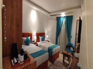 una camera d'albergo con due letti e una televisione di Pyramids Gem Plaza Hotel & Suites a Il Cairo
