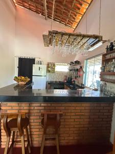 eine Küche mit einer Theke und 2 Stühlen an einer Bar in der Unterkunft Hostel Caraivando in Caraíva
