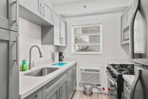 uma cozinha branca com um lavatório e um fogão em Balcony Chic Apt, w/2 Queenbeds, on Ocean Dr Beach em Miami Beach
