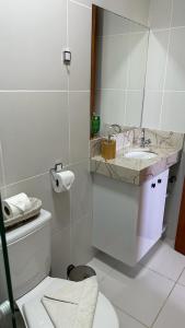 La salle de bains blanche est pourvue de toilettes et d'un lavabo. dans l'établissement Apartamento Doce Lar Resort Treebies Subauma, à Subaúma