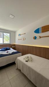 um quarto com duas camas e uma prancha de surf na parede em Apartamento Doce Lar Resort Treebies Subauma em Subaúma