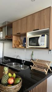 eine Küche mit einer Theke mit einer Spüle und einer Mikrowelle in der Unterkunft Apartamento Doce Lar Resort Treebies Subauma in Subaúma