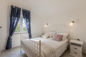 a bedroom with a white bed with blue curtains at Apartments by the sea Milna, Vis - 8946 in Rukavac