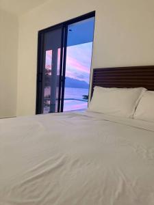 a bedroom with a white bed and a large window at Villa Sunrise RD in Las Galeras