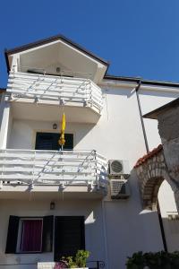 a white building with a balcony with a yellow flag at Studio Gradac 15642b in Gradac