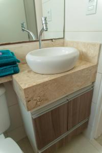 a white sink on a wooden counter in a bathroom at Apartamento privativo Pindamonhangaba-SP in Pindamonhangaba