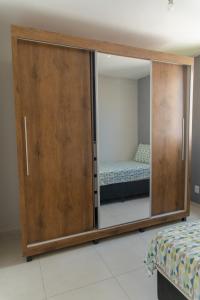 a large wooden cabinet with a mirror in a bedroom at Apartamento privativo Pindamonhangaba-SP in Pindamonhangaba