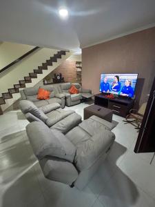uma sala de estar com um sofá e uma televisão em Casa Bege - Gaia aluguel temporada Mcz em Maceió