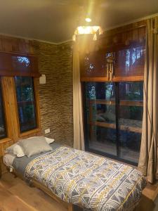 een slaapkamer met een bed voor een raam bij cabaña del bosque in Villarrica