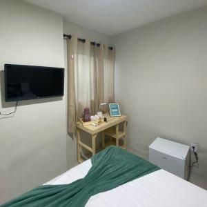 a bedroom with a bed and a desk with a television at Sam Day Suites in Natal