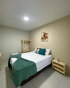 a bedroom with a large bed with a green blanket on it at Sam Day Suites in Natal