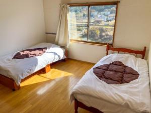 two beds in a room with a window at 【MeTeL】窓辺から壮大な富士が拝める。リノベーション済み一等貸し宿泊施設 in Nishikatsuracho